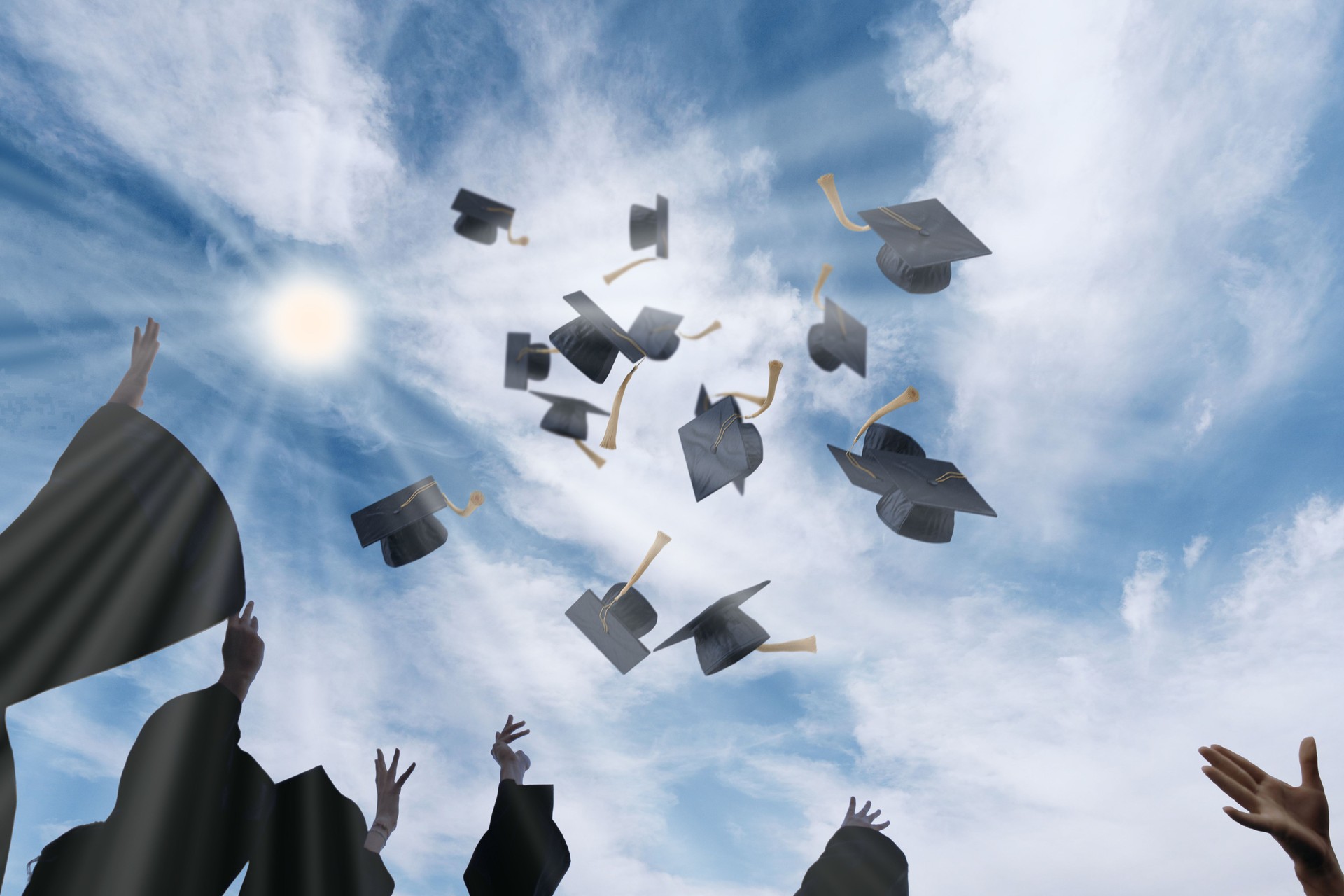 Graduating Students Throwing Graduation Caps in the Air Against Blue Sky