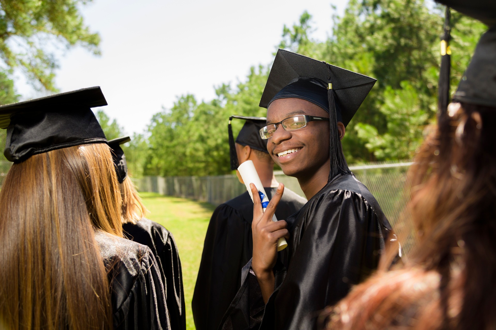 Education: African descent graduate holds diploma after graduation. Friends.